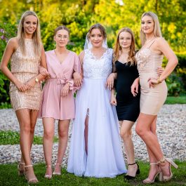 Pamiątkowe zdjęcie panny młodej z przyjaciółkami w plenerze podczas wesela.