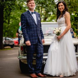 Para Młoda pozuje do pamiątkowego zdjęcia z limuzyną ślubną - Fiat 125p